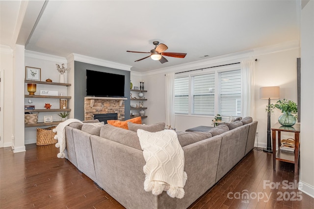 living room featuring a stone fireplace, ceiling fan, dark hardwood / wood-style flooring, and ornamental molding