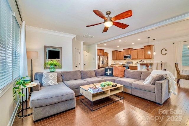 living room with wood-type flooring, ornamental molding, and ceiling fan