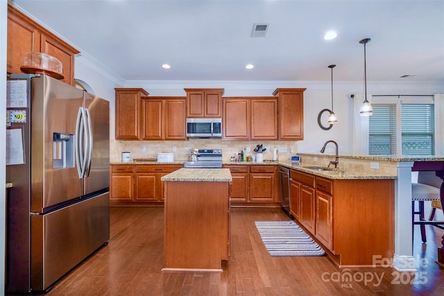 kitchen with sink, a breakfast bar area, hanging light fixtures, kitchen peninsula, and stainless steel appliances