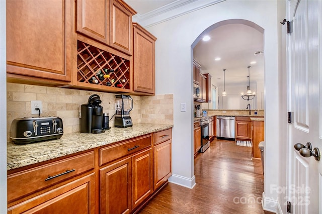 bar featuring dark hardwood / wood-style floors, decorative backsplash, hanging light fixtures, stainless steel appliances, and crown molding