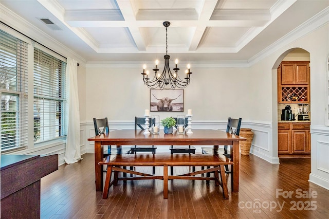 dining space with coffered ceiling, crown molding, a chandelier, dark hardwood / wood-style floors, and beamed ceiling