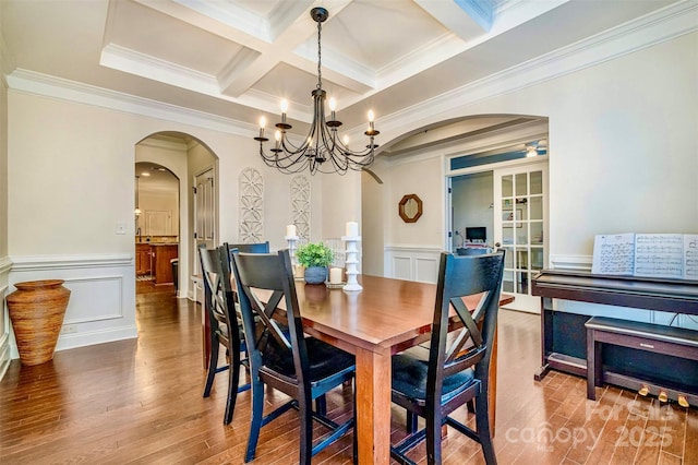 dining room featuring hardwood / wood-style floors, beamed ceiling, ornamental molding, coffered ceiling, and an inviting chandelier