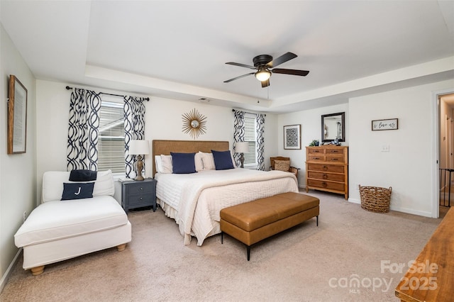 carpeted bedroom featuring a raised ceiling and ceiling fan