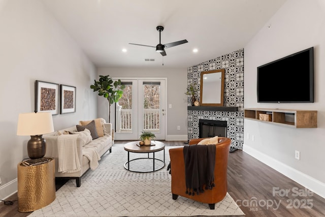 living room featuring ceiling fan, hardwood / wood-style floors, and a fireplace