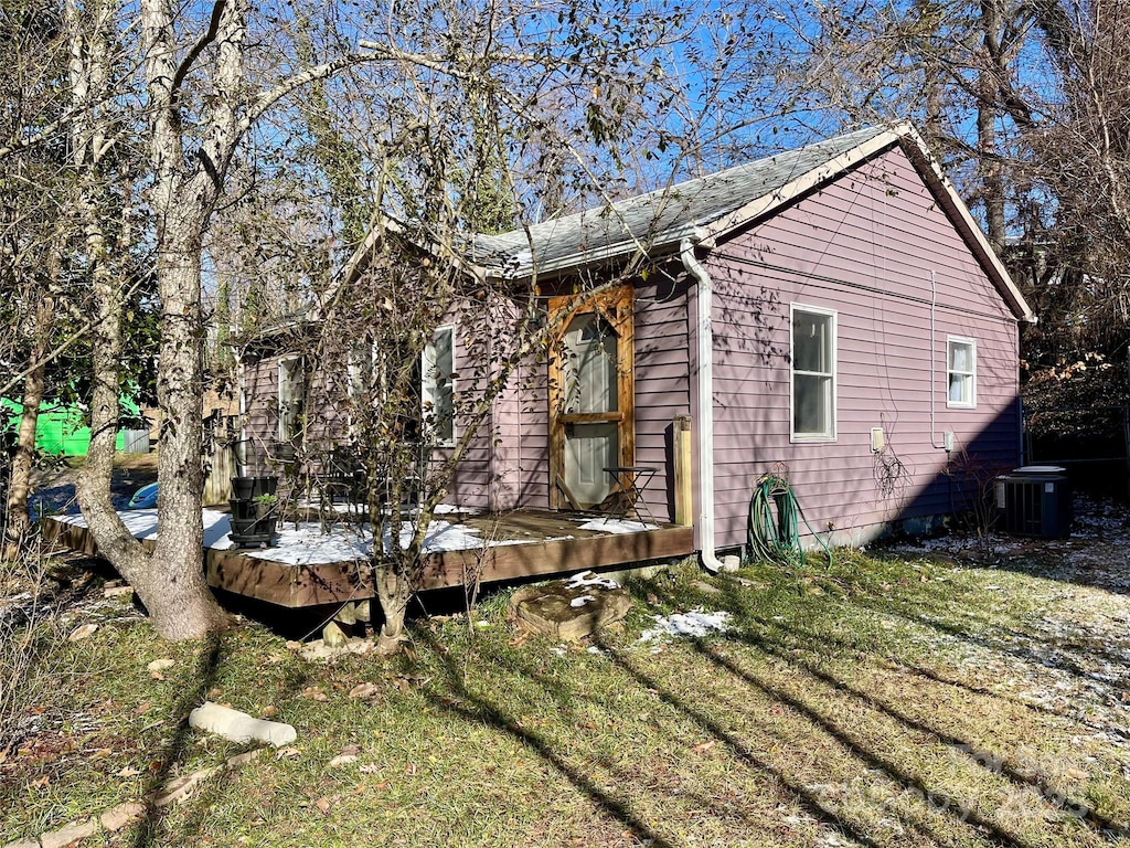 view of property exterior featuring central AC unit, a deck, and a yard