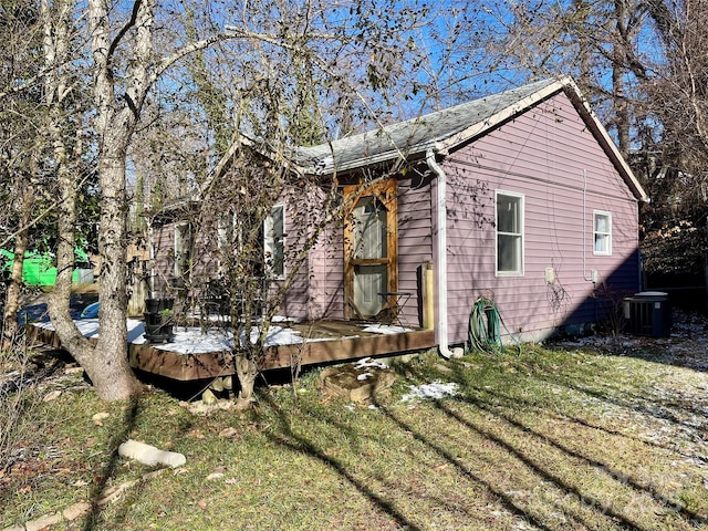 view of property exterior featuring central AC unit, a deck, and a yard