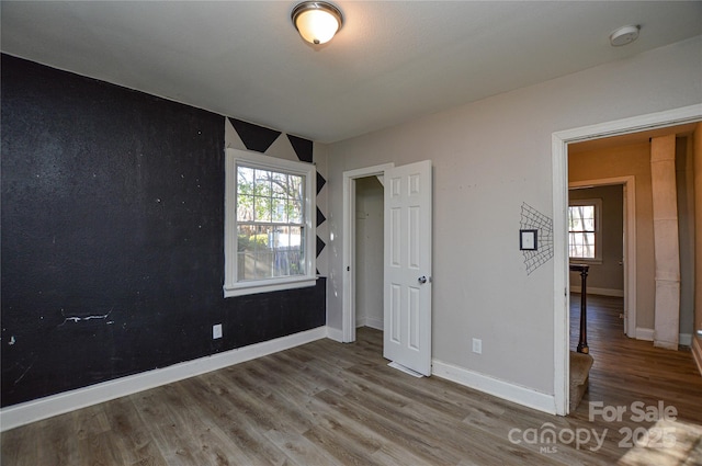 unfurnished bedroom featuring hardwood / wood-style floors and multiple windows