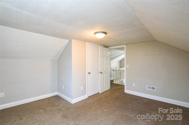 additional living space featuring a textured ceiling, carpet floors, and vaulted ceiling