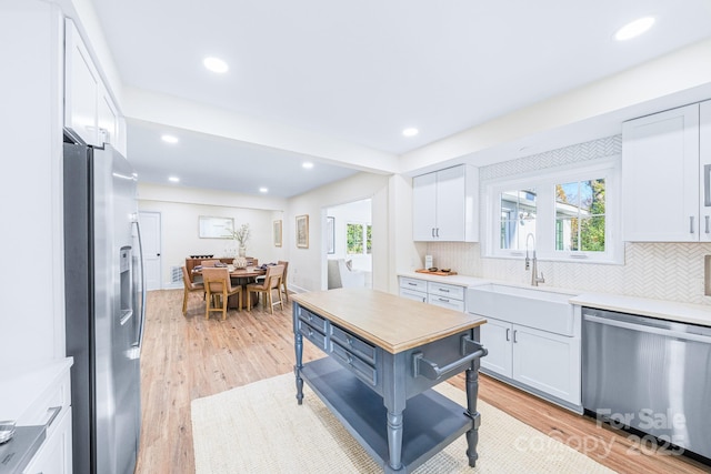 kitchen featuring appliances with stainless steel finishes, sink, white cabinets, and light hardwood / wood-style floors