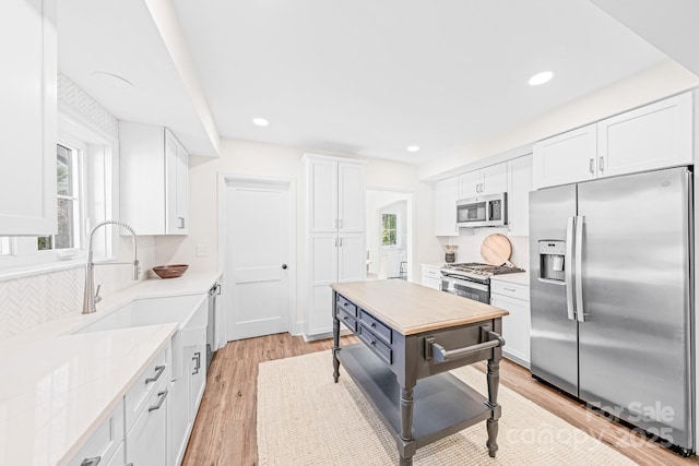 kitchen featuring white cabinetry, sink, stainless steel appliances, and light wood-type flooring