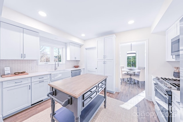 kitchen with stainless steel appliances, white cabinetry, sink, and a wealth of natural light