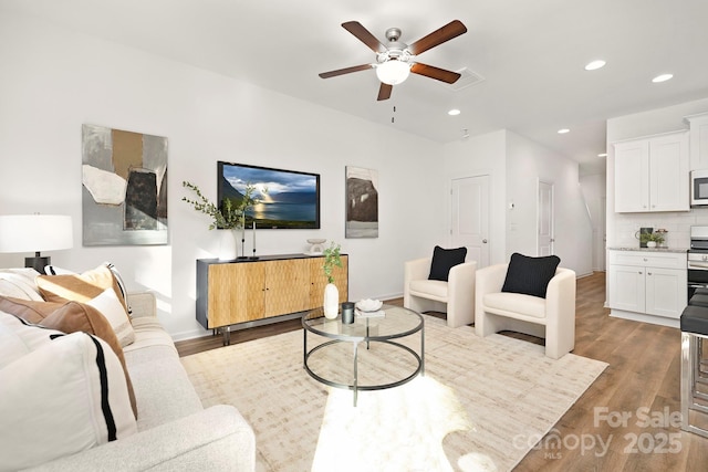 living room featuring light hardwood / wood-style flooring and ceiling fan