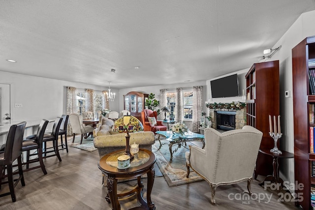 living room with a fireplace, hardwood / wood-style floors, a textured ceiling, and a notable chandelier