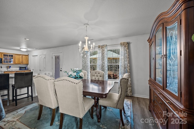 dining space featuring a textured ceiling, dark hardwood / wood-style floors, and a notable chandelier