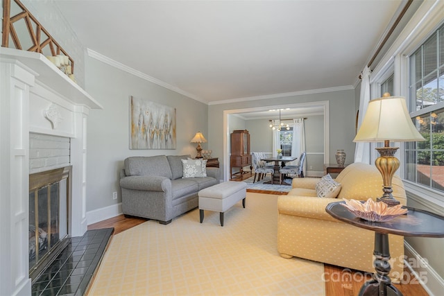 living room featuring a brick fireplace, wood-type flooring, ornamental molding, and a healthy amount of sunlight