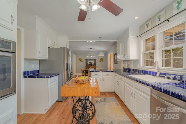 kitchen with sink, white cabinets, kitchen peninsula, stainless steel appliances, and light hardwood / wood-style flooring