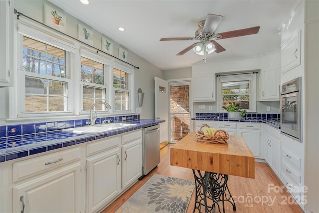 kitchen featuring appliances with stainless steel finishes, tile counters, sink, and white cabinets