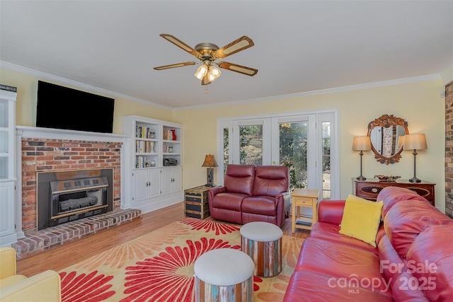 living room with french doors, ornamental molding, a brick fireplace, and light hardwood / wood-style flooring