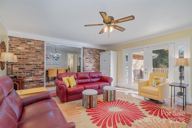 living room featuring crown molding, light hardwood / wood-style floors, brick wall, ceiling fan with notable chandelier, and french doors