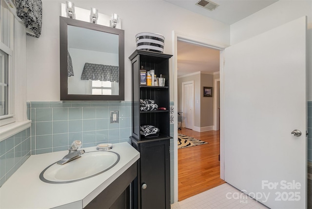 bathroom featuring ornamental molding, vanity, hardwood / wood-style floors, and tile walls