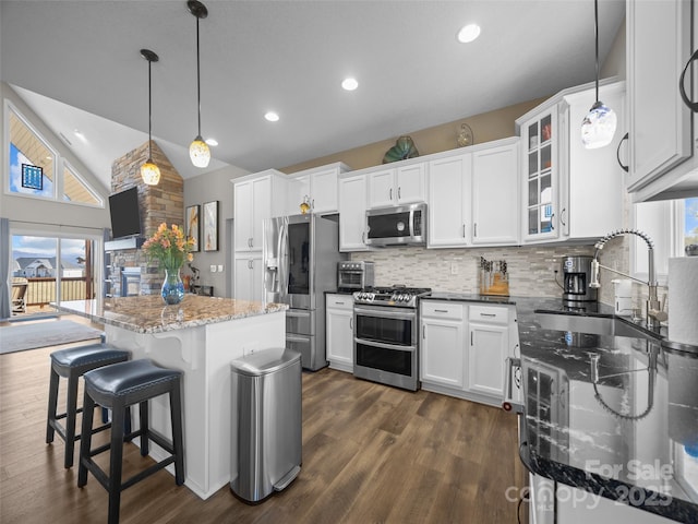 kitchen with vaulted ceiling, decorative light fixtures, white cabinetry, backsplash, and stainless steel appliances