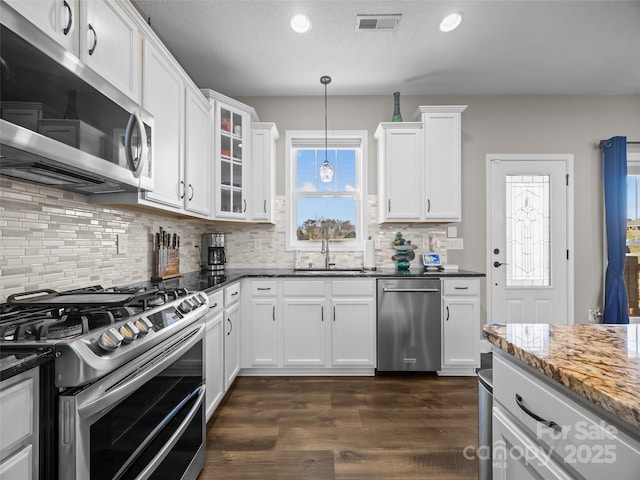 kitchen featuring pendant lighting, white cabinetry, stainless steel appliances, and dark stone counters