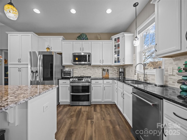 kitchen with stainless steel appliances, dark stone countertops, white cabinets, and decorative light fixtures