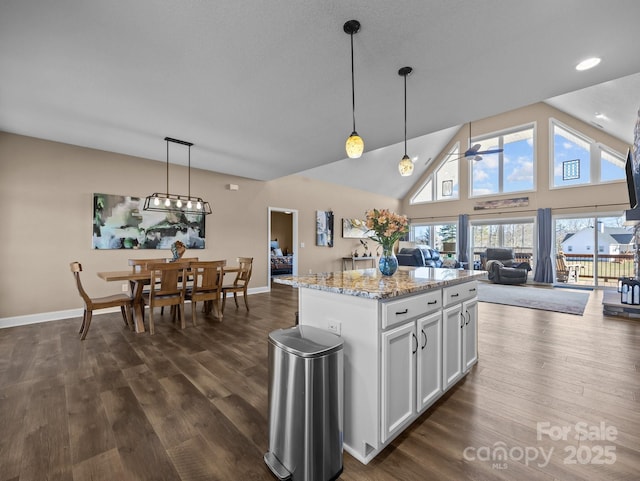 kitchen with a kitchen island, white cabinets, hanging light fixtures, ceiling fan, and light stone countertops