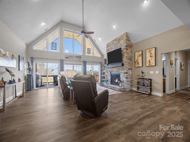 living room with dark hardwood / wood-style floors, ceiling fan, a fireplace, and high vaulted ceiling