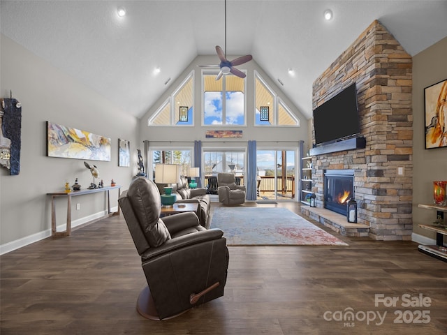 living room with ceiling fan, dark hardwood / wood-style flooring, high vaulted ceiling, and a fireplace