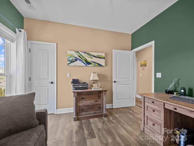 office with plenty of natural light, hardwood / wood-style floors, and a textured ceiling