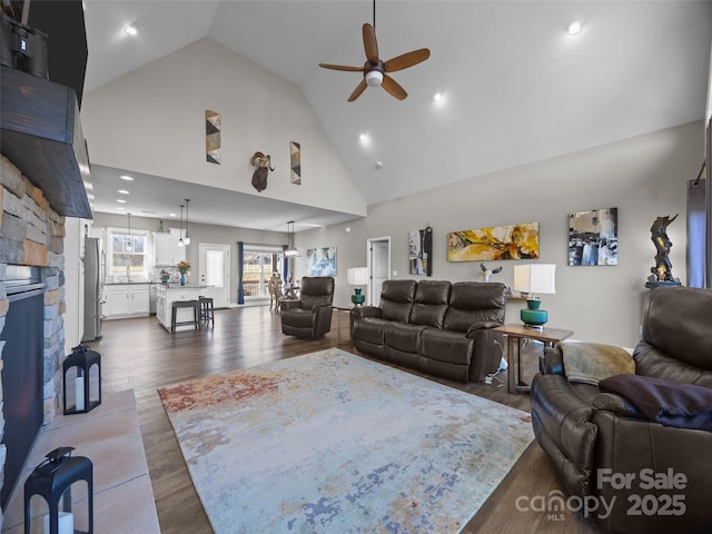 living room featuring sink, high vaulted ceiling, hardwood / wood-style flooring, ceiling fan, and a fireplace