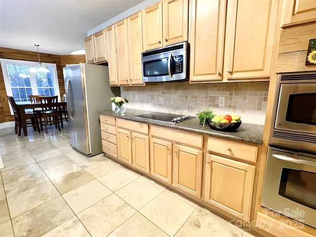 kitchen with dark stone counters, decorative backsplash, hanging light fixtures, stainless steel appliances, and light brown cabinets