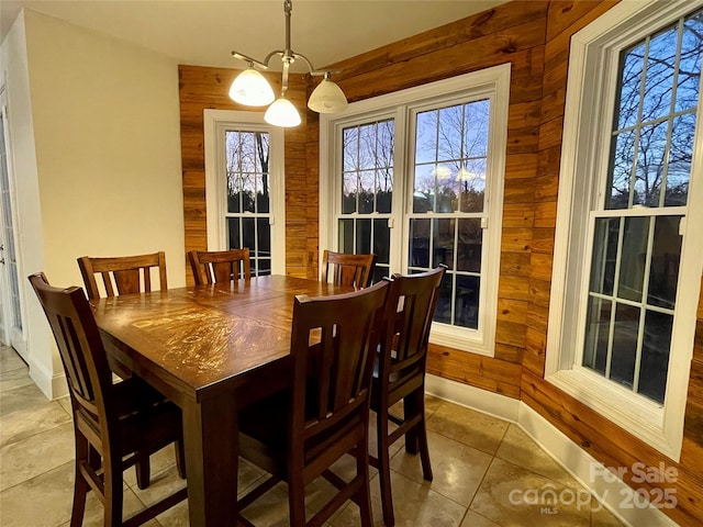 tiled dining area with wood walls and a chandelier