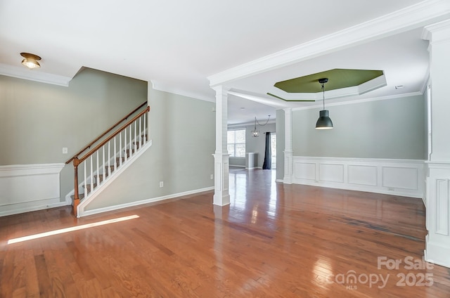 unfurnished living room with a raised ceiling, crown molding, hardwood / wood-style floors, and a chandelier