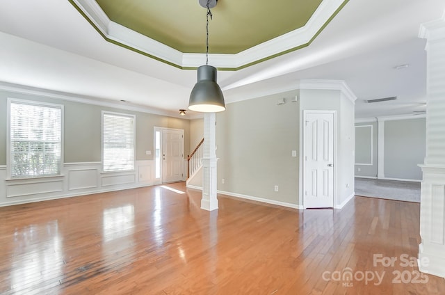 empty room featuring a tray ceiling, light hardwood / wood-style flooring, and crown molding