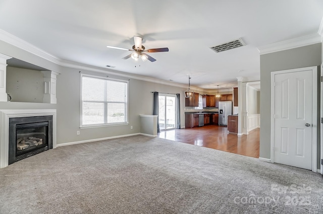 unfurnished living room featuring crown molding, ceiling fan, and dark carpet