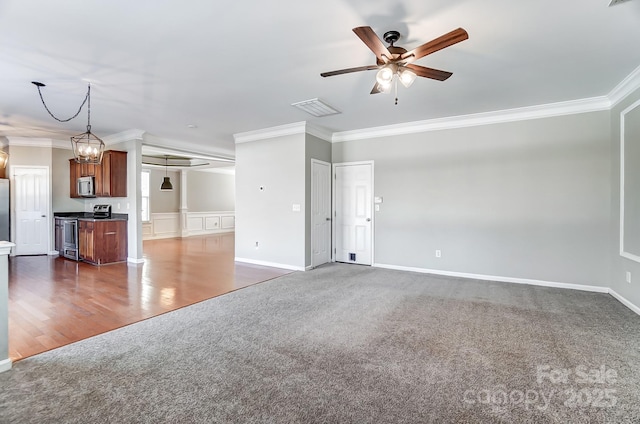 unfurnished living room with crown molding, ceiling fan with notable chandelier, and dark colored carpet