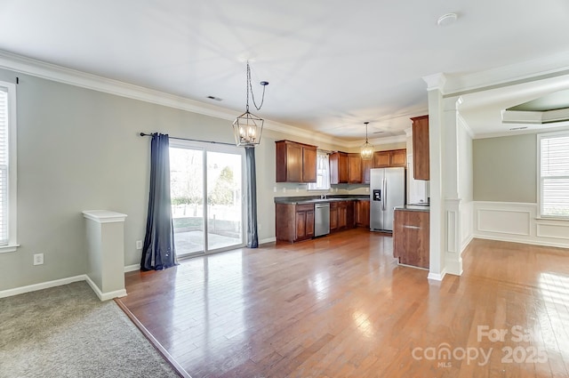 kitchen featuring pendant lighting, ornamental molding, and stainless steel appliances