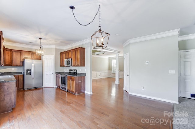 kitchen with pendant lighting, an inviting chandelier, hardwood / wood-style flooring, ornamental molding, and appliances with stainless steel finishes