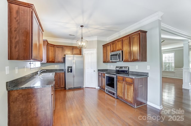 kitchen with decorative light fixtures, stainless steel appliances, crown molding, and light hardwood / wood-style floors