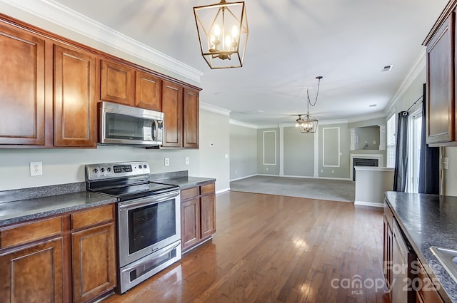 kitchen with a chandelier, appliances with stainless steel finishes, decorative light fixtures, and ornamental molding