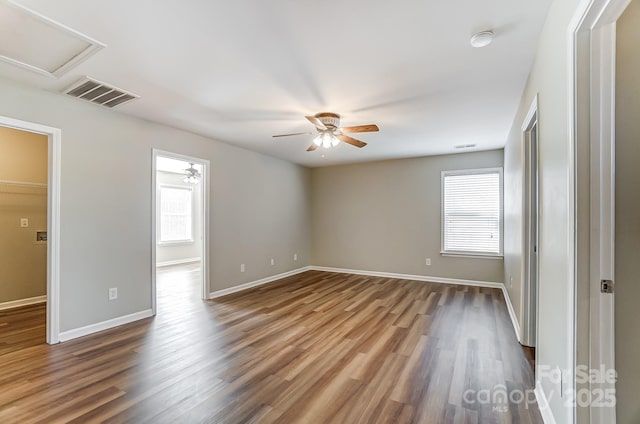 interior space featuring a walk in closet, ceiling fan, a closet, and dark wood-type flooring