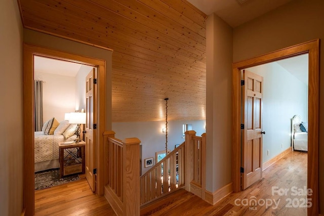 corridor featuring light wood-type flooring and wooden ceiling