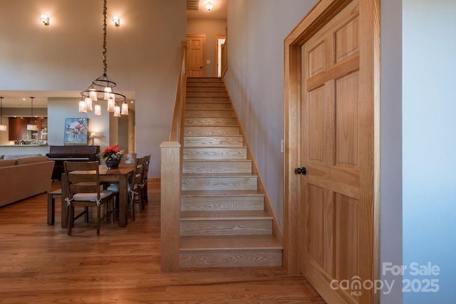 staircase with an inviting chandelier and hardwood / wood-style flooring