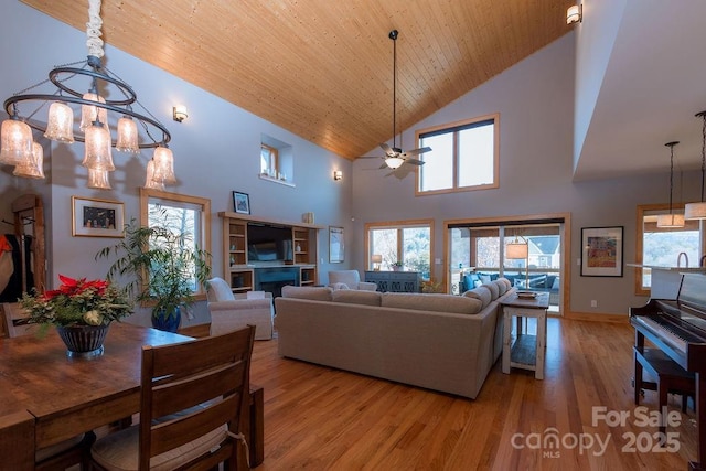 living room featuring a high ceiling, ceiling fan with notable chandelier, light hardwood / wood-style floors, and wooden ceiling