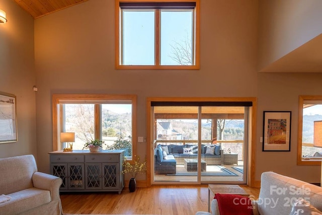 living room with high vaulted ceiling, light wood-type flooring, and wooden ceiling