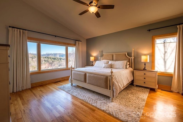 bedroom with ceiling fan, light hardwood / wood-style floors, lofted ceiling, and a mountain view