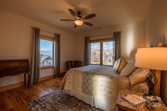 bedroom with ceiling fan, multiple windows, and hardwood / wood-style flooring