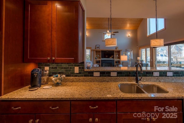 kitchen with decorative light fixtures, light stone counters, and sink